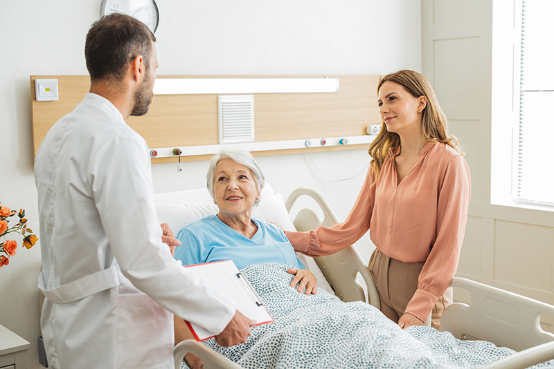 Adult woman utilizing ways to advocate for a senior loved one with the doctor and her elderly mother in the hospital